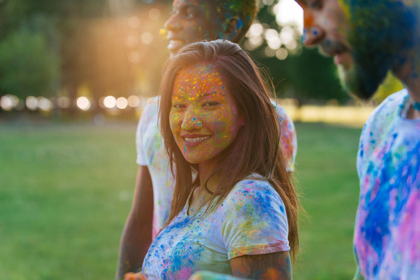 Group of teens playing with colors at the holi festival, in a park - Fotó, kép