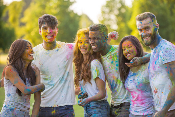 Group of teens playing with colors at the holi festival, in a park - Zdjęcie, obraz