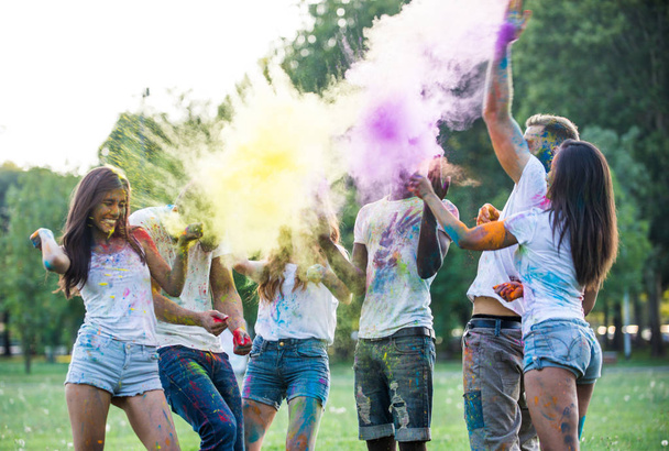 Group of teens playing with colors at the holi festival, in a park - Фото, изображение