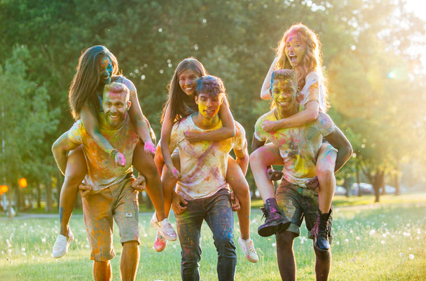 Group of teens playing with colors at the holi festival, in a park - Photo, Image
