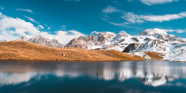 Nagy magasságban alpesi tó idilli föld tükörképe a fenséges sziklás hegyi csúcsok. Széles szög kilátás a teljes Alpokra. Réce narancssárga megjelenés. - Fotó, kép