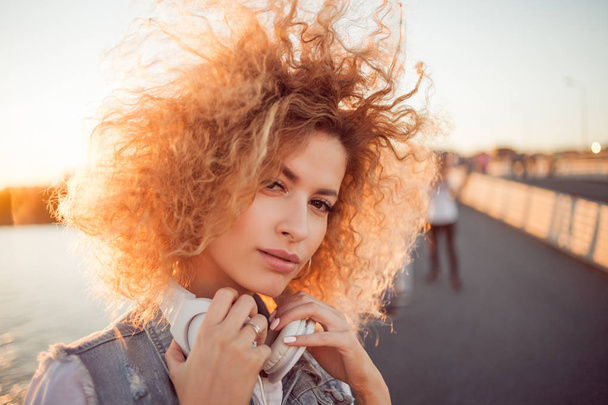Chica de moda con auriculares grandes en un paseo por la ciudad, de cerca
 - Foto, imagen