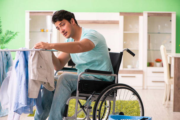 Людина з обмеженими можливостями на інвалідному візку займається пранням
 - Фото, зображення