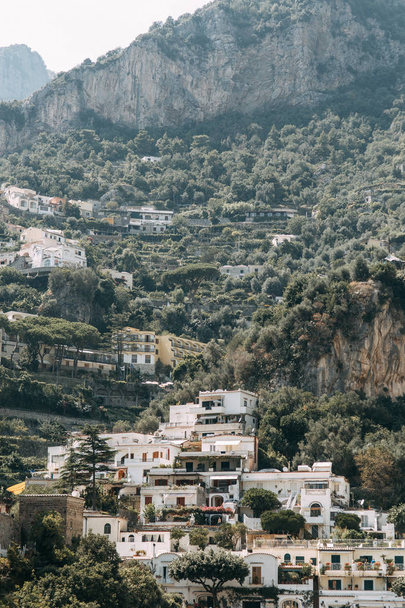 The coast of Positano, Amalfi in Italy. Panorama of the evening city and the streets with shops and cafes. Houses by the sea and the beach. Ancient architecture and temples. View from a postcard on top - Photo, image