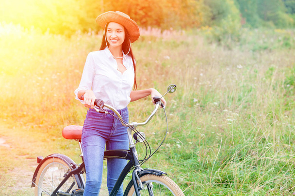 Nő, egy fekete biciklit a nyári park vagy az erdő - Fotó, kép