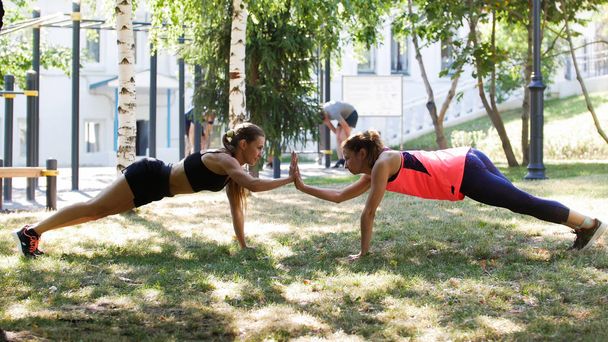 Two girlfriend perform the exercise together to help each other - Photo, Image