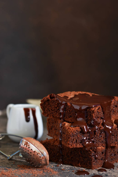 Brownie is a classic American dessert. Pie with chocolate sauce on a dark background. - Foto, afbeelding