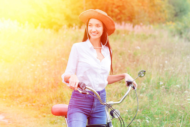 Nainen, jolla on musta polkupyörä kesäpuistossa tai metsässä
 - Valokuva, kuva