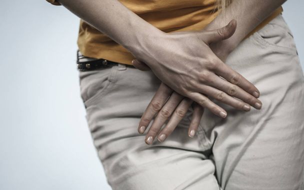 Closeup young sick woman with hands holding pressing her crotch lower abdomen. Medical or gynecological problems, healthcare concept - Fotó, kép