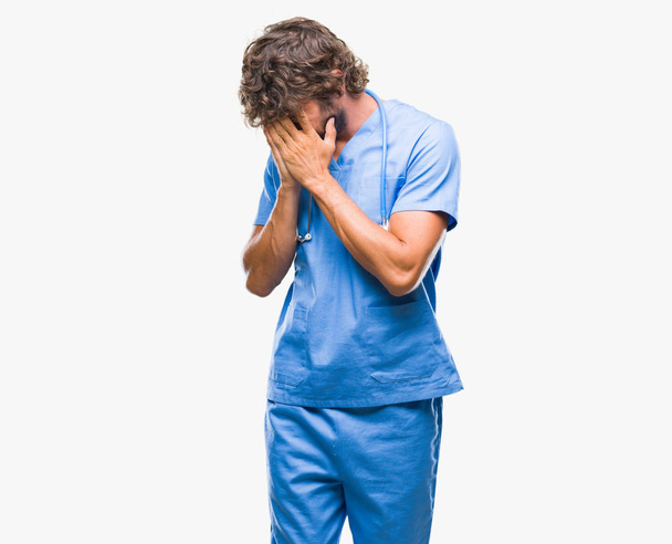 Красивый латиноамериканец-хирург на изолированном фоне с грустным лицом, прикрывающим лицо руками во время плача. Концепция депрессии
. - Фото, изображение
