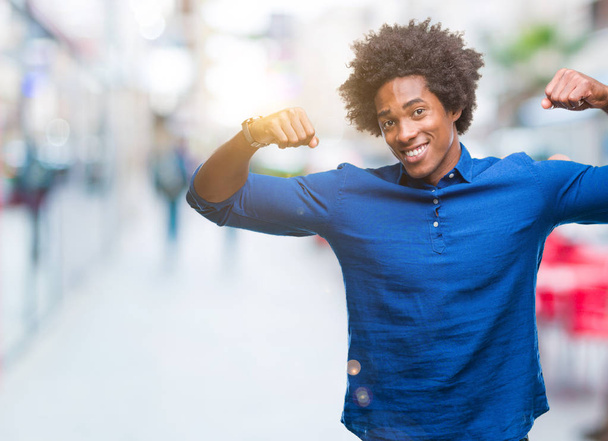 Афро американський людини над ізольованих фон показані м'язи рук посміхаючись пишається тим. Концепція фітнес. - Фото, зображення