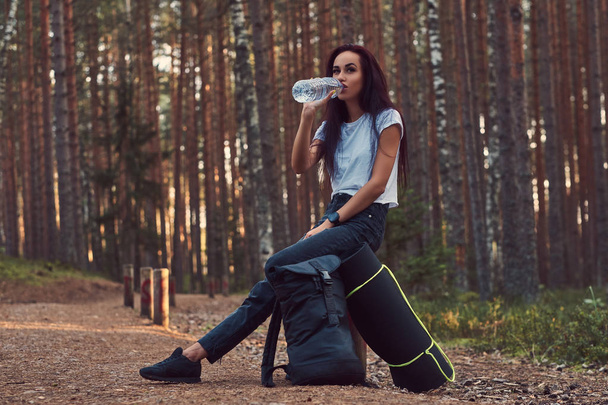 Turysta dziewczyna zatrzymał się na odpoczynek i napił się wody w piękny jesienny Las. - Zdjęcie, obraz