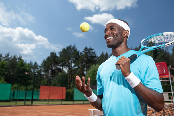 Cheerful man is using tennis equipment outside - Foto, Imagen