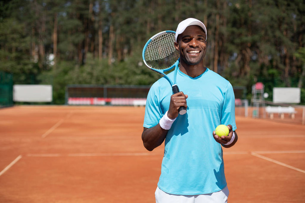 Smiling man is going to play tennis outdoor - Fotoğraf, Görsel