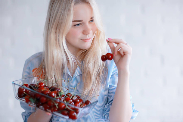 cute young blonde woman eating fresh cherries  - Photo, image