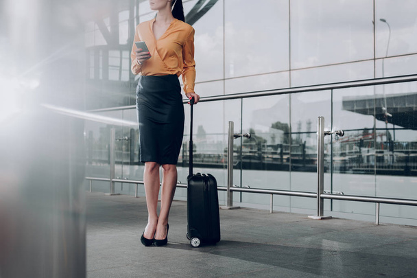 Brunette woman with suitcase is waiting for flight - Фото, изображение