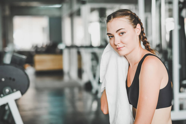 Young Caucasian woman wiped off her sweat and rest in gym after workout - Фото, зображення