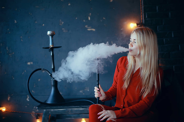 attractive young blonde woman in red clothes smoking hookah - Foto, afbeelding