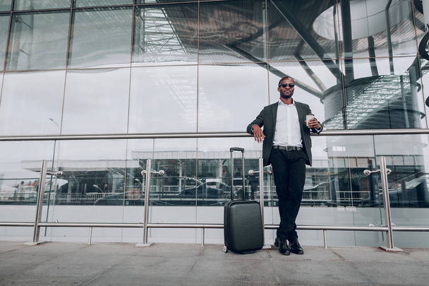 Erwachsener Geschäftsmann steht neben Flughafen und hält Tasse Kaffee - Foto, Bild