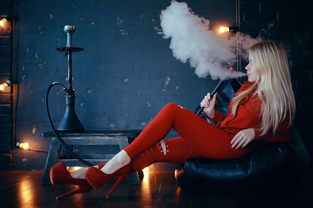 attractive young blonde woman in red clothes smoking hookah - 写真・画像