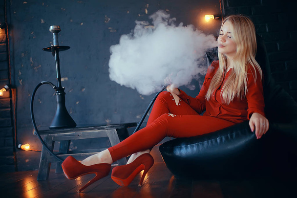 attractive young blonde woman in red clothes smoking hookah - Fotó, kép