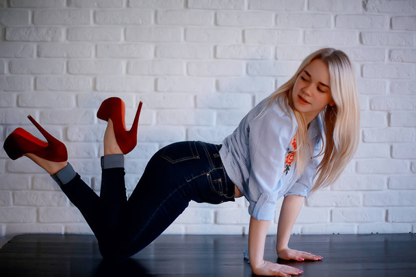 attractive young blonde woman wearing jeans and red high-heeled shoes - Foto, Imagen