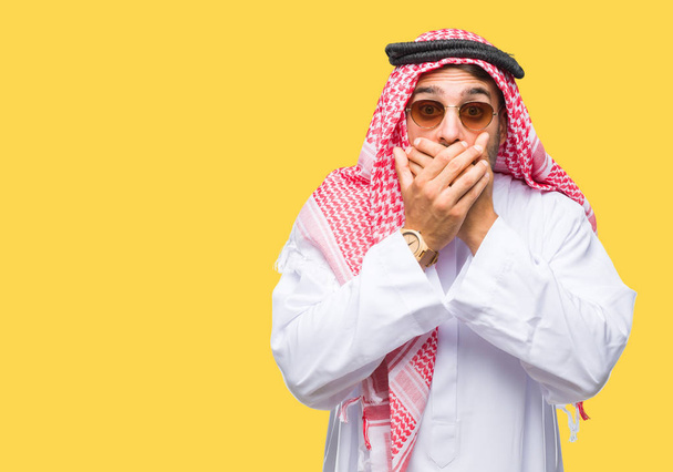 Jovem homem bonito vestindo keffiyeh sobre fundo isolado chocado cobrindo a boca com as mãos por engano. Conceito secreto
. - Foto, Imagem