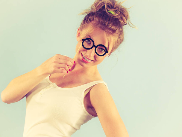 Elegant young woman pretending wearing funny nerd eyeglasses. Education and studying females look concept. - Foto, Imagen
