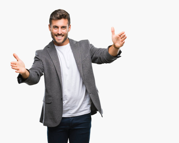 Young handsome business man over isolated background looking at the camera smiling with open arms for hug. Cheerful expression embracing happiness. - Photo, Image
