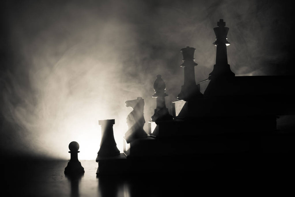 事業階層。チェスの駒の戦略コンセプト。チェス上部王と書籍のピラミッドの上に立っています。トーンの光で暗い霧の背景。コピー スペース. - 写真・画像