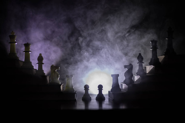 Business hierarchy. Strategy concept with chess pieces. Chess standing on a pyramid of books with the king at the top. Dark foggy background with toned light. Copy space. - Photo, Image