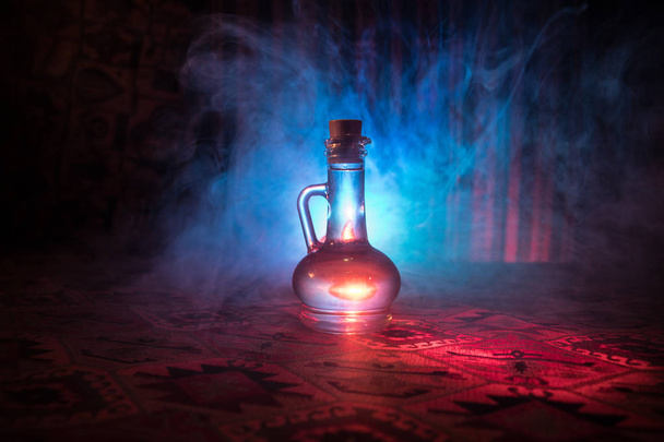 Αντικέ και vintage γυάλινο μπουκάλι σε σκοτεινό ομιχλώδες φόντο με το φως. Δηλητήριο ή μαγικό υγρό έννοια. - Φωτογραφία, εικόνα