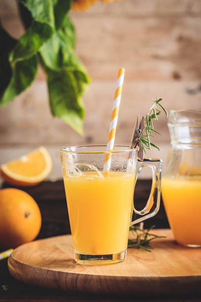 Glass of fresh pressed orange juice and oranges on wooden table. Autumn cozy rustic mood still life - Фото, зображення