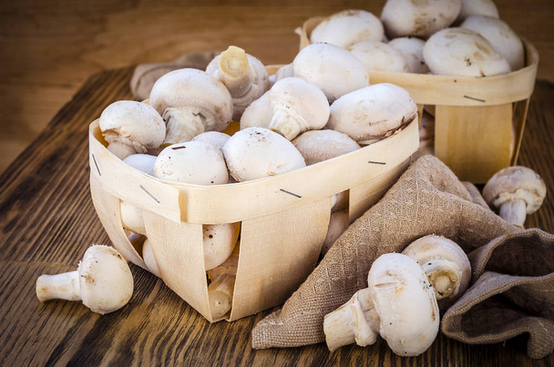 Fresh champignon mushrooms in a basket on wooden table - Photo, Image