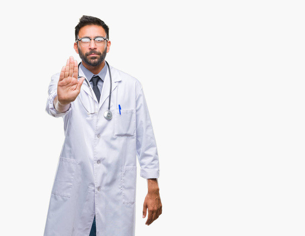 Ενηλίκων Ισπανόφωνος γιατρός άνδρα πάνω σε μια απομονωμένη φόντο κάνει στάση τραγουδήσει με την παλάμη του χεριού. Προειδοποίηση έκφραση με αρνητικές και σοβαρές χειρονομία στο πρόσωπο. - Φωτογραφία, εικόνα