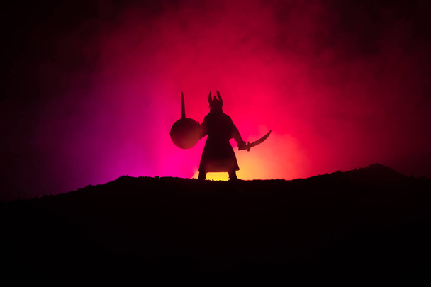 Bojovník s mečem silueta na obloze. Středověký rytíř s mečem na tmavém pozadí mlhavé tónovaný. Selektivní fokus - Fotografie, Obrázek