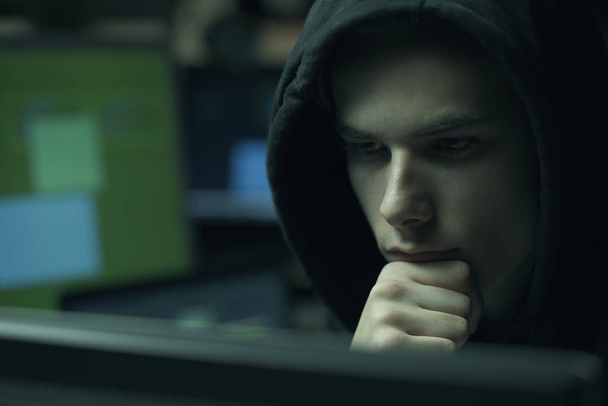 Cool joven hacker con sudadera con capucha que trabaja con computadoras, cibercrimen y concepto de seguridad de datos
 - Foto, Imagen