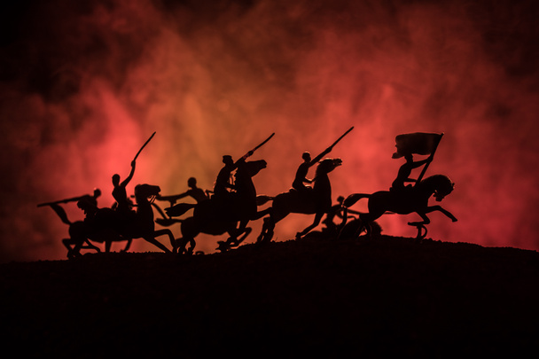 Офицер Мировой Войны (или воин) всадник на коне с мечом, готовым к бою, и солдаты на темном туманном фоне. Поле битвы боевых солдат. Селективный фокус
 - Фото, изображение