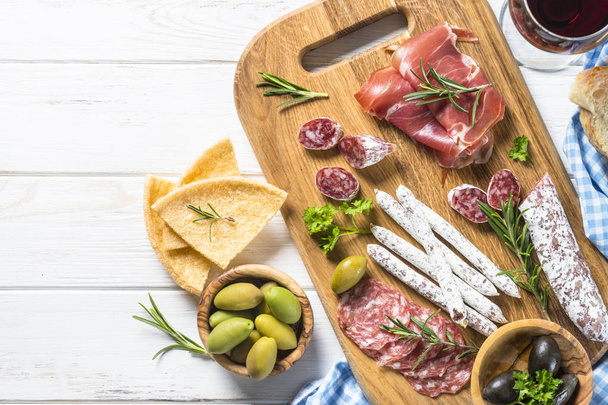 Tradiční italský předkrmů, plátky masa se víno a olivy na bílém stole. Pohled shora, kopie prostor. - Fotografie, Obrázek