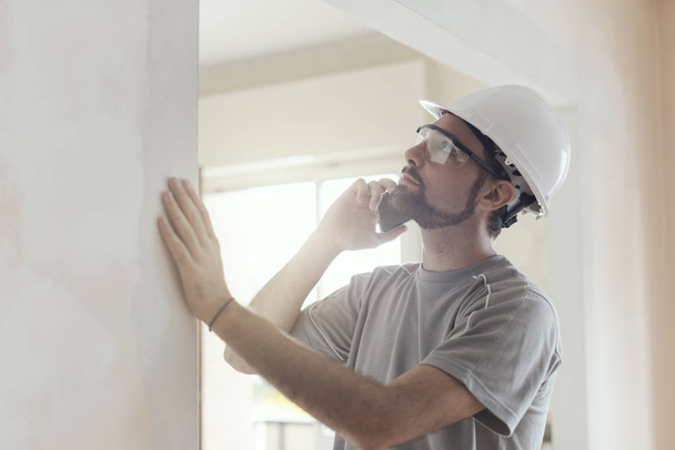 Professional builder with safety helmet having a phone call, home renovation and communication concept - Фото, зображення