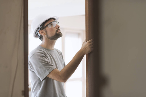 Professional carpenter installing a door jamb, home renovation and carpentry concept - Photo, Image
