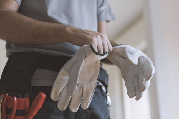 Professional repairman wearing protective gloves: home renovationa and safety concept - Valokuva, kuva