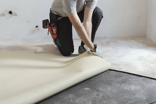 Professional contractor removing an old linoleum flooring: home renovation concept - Foto, afbeelding