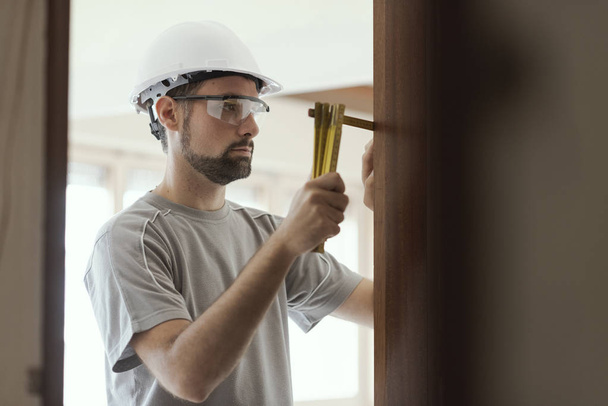 Carpenter taking measures with a folding ruler: home renovation and construction concept - Foto, Imagem