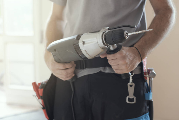Professional repairman working with a drill and renovating an apartment, home makeover concept - Φωτογραφία, εικόνα