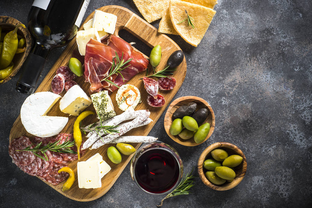 Antipasto board with sliced meat, ham, salami, cheese, olives and red wine. Top view with copy space. - Foto, afbeelding