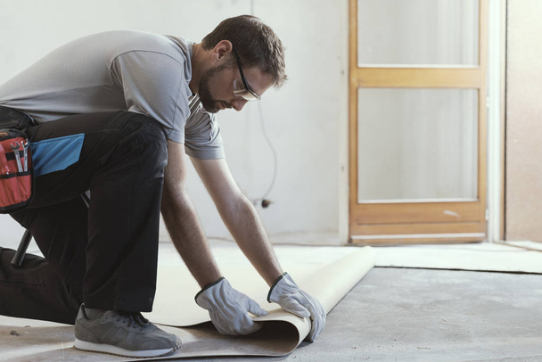 Professional contractor removing an old linoleum flooring: home renovation concept - Photo, image