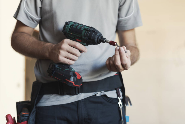 Professional handyman changing a drill bit: home renovation and manual work concept - Valokuva, kuva
