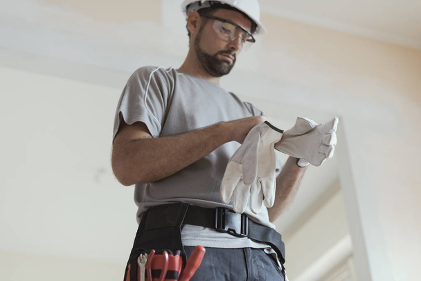 Professional repairman wearing protective gloves: home renovationa and safety concept - Fotografie, Obrázek