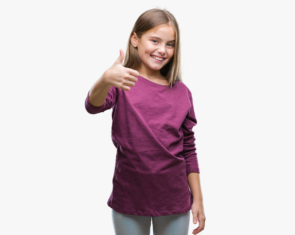 Young beautiful girl over isolated background doing happy thumbs up gesture with hand. Approving expression looking at the camera with showing success. - Photo, image